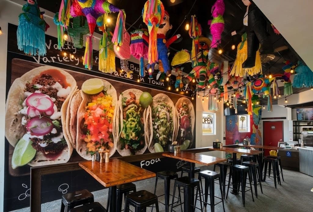 Restaurant interior with colorful piñatas and taco mural