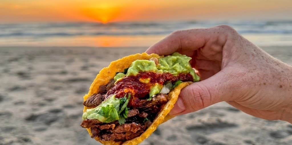 Baja taco held up against a Mission Beach sunset